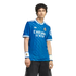 A man wearing a blue Real Madrid soccer jersey with white accents and matching wristbands, standing against a solid black background.