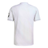 Back view of a white short-sleeved sports shirt with a subtle textured mesh and a black circular logo on the left sleeve, isolated on a white background.