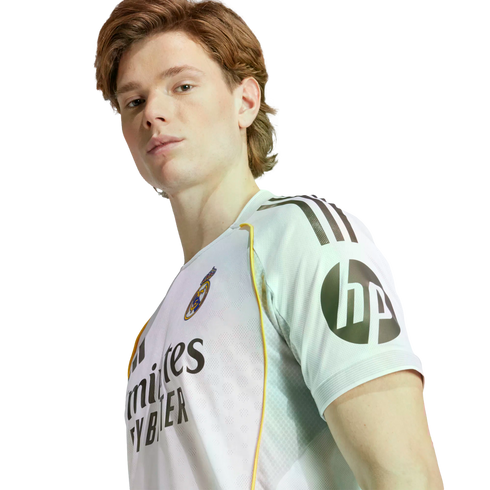 A young man wearing a white Real Madrid soccer jersey with an HP logo on the sleeve, posing against a plain white background.
