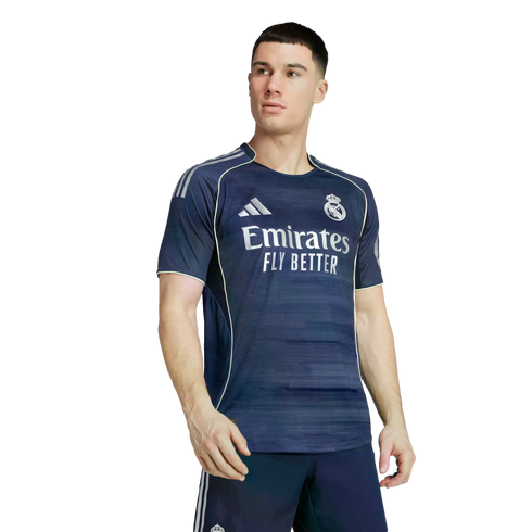 Male model wearing a navy blue Real Madrid soccer jersey with white sponsor text and light green piping against a white background.