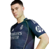 Young man wearing a navy Real Madrid training jersey with silver logos and neon green trim, posing against a white background.
