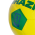A close-up of a yellow and green soccer ball featuring the word "BRAZIL" and a blue FIFA "Official Licensed Product" logo with a World Cup trophy silhouette on a green pentagonal panel.