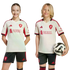 A girl and a boy wearing matching Liverpool FC jerseys and shorts smile against a black background. The boy holds a soccer ball.
