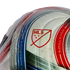 Close-up of an MLS soccer ball featuring the red league logo and geographic coordinates printed along curved blue and red stripes on a white textured surface.