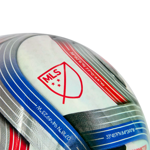 Close-up of a textured soccer ball featuring the red MLS logo and geographic coordinates printed on blue and red stripes.
