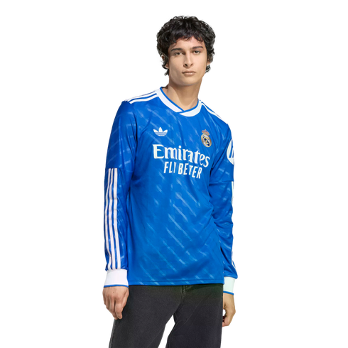 Man wearing a blue long-sleeved Real Madrid soccer jersey with white trim and Emirates sponsor logo.