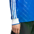 Blue long-sleeve shirt with three white stripes on the sleeve, white cuffs, and a diagonal pattern. Hand and dark pants are visible.