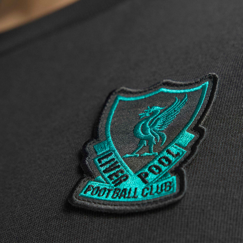 Embroidered teal and black Liverpool Football Club crest patch with Liver bird, stitched onto dark textured fabric.