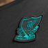 Embroidered teal and black Liverpool Football Club crest patch with Liver bird, stitched onto dark textured fabric.