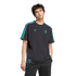 A man in a black Adidas x Liverpool FC tee with teal accents and logos, wearing black joggers, against a solid black backdrop.