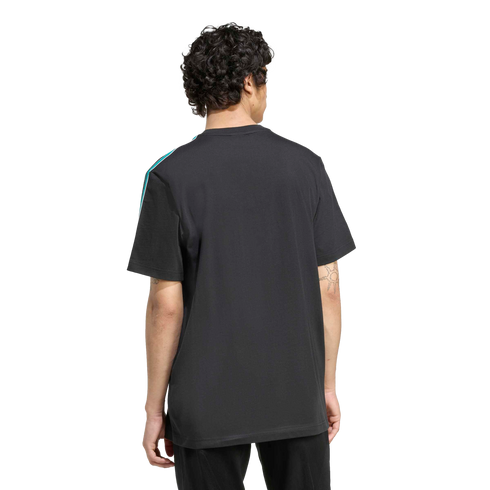 Back view of a man with curly hair wearing a black t-shirt with a teal and white shoulder stripe, against a solid black background.