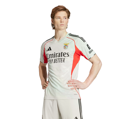 Man wearing a light grey and red SL Benfica soccer kit, standing with hands on hips against a white background.