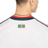 Close-up of the back of a white jersey with a 'SOMOS MÉXICO' logo and a red and green collar. A silver chain necklace is visible on the person's neck against a black background.