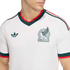 Close-up of a white Mexico national team soccer jersey featuring green and red trim, the team crest, and a green Adidas logo.