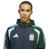 A man with a buzz cut wearing an Adidas Argentina national football team zip-up jacket against a black background.