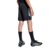 Rear view of a person wearing black Adidas athletic shorts and t-shirt, tall black socks, and black and neon yellow soccer cleats against a plain gray background.