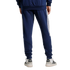 Rear view of a person wearing navy Adidas track pants with white side stripes and white sneakers against a light gray background.