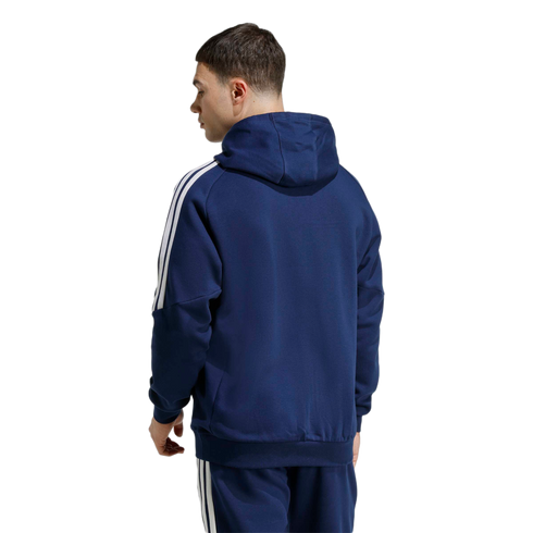 A man from the back wearing a navy blue Adidas zip-up hoodie and matching joggers, both featuring the iconic white three-stripes down the sides.