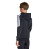 Rear view of a boy in a black Adidas hoodie with white stripes on the sleeves and matching sweatpants, standing against a plain light gray background.