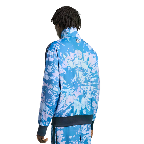 A person from behind wearing a blue and purple tie-dye tracksuit with a small circular logo on the jacket back. Solid black background.