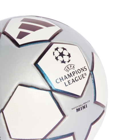 Close-up of a silver and white UEFA Champions League mini replica soccer ball with star panels and logos on a solid black background.