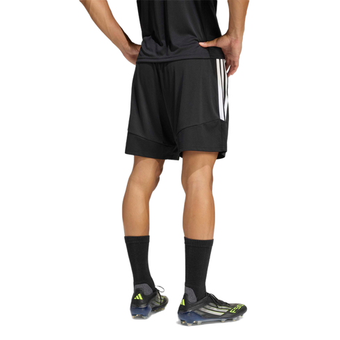 Rear view of a person wearing black Adidas athletic shorts, a black shirt, and soccer cleats against a plain white background.