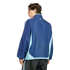 Back view of a man wearing a navy and light blue color-blocked track jacket and dark striped pants, looking over his shoulder against a black background.