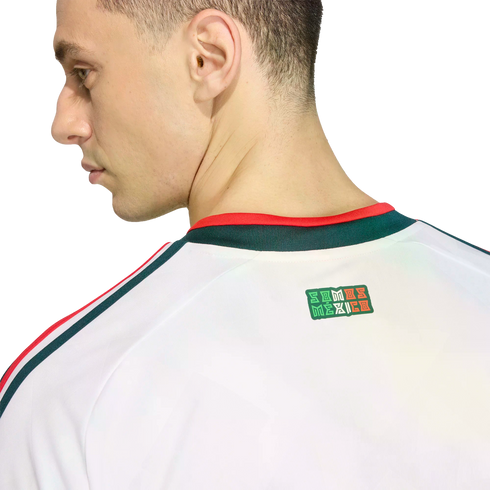 Profile of a man wearing a white jersey with red and green accents. A "SOMOS MÉXICO" graphic is visible on the upper back below the collar. Black background.