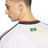 Profile of a man wearing a white jersey with red and green accents. A "SOMOS MÉXICO" graphic is visible on the upper back below the collar. Black background.
