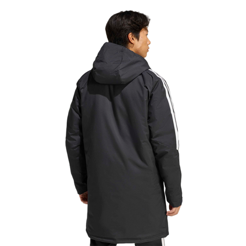 Rear view of a man in a long black hooded parka with white stripes on the sleeves, against a light gray background.