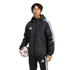 Man wearing a black Adidas puffer jacket and tracksuit pants, holding a soccer ball against a solid black background.