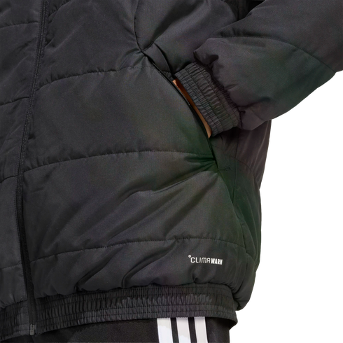Close-up of a black quilted jacket featuring a hand in the pocket, ribbed hem and cuffs, and "CLIMAWARM" branding. White-striped pants are partially visible at the bottom.