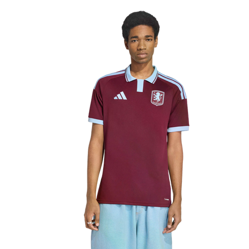 A man models a maroon and light-blue Adidas soccer jersey with a polo collar and a lion crest on the chest, standing against a white background.
