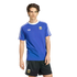 A young man with wavy brown hair models a royal blue Adidas Argentina national football team t-shirt and matching black athletic shorts against a solid black background.
