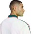 Profile of a man with a buzz cut wearing a white Mexico jacket with green and red trim, set against a black background.