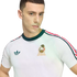 A close-up of a young man wearing a white retro Mexico National Team t-shirt by Adidas. The shirt features a dark green crew neck, a green Adidas Trefoil logo on the right, and the Mexican National Team crest on the left. Three stripes in green, white, an