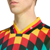 Close-up of a person wearing a vibrant harlequin-patterned jersey in red, yellow, black, and teal, featuring a German flag-colored striped collar.