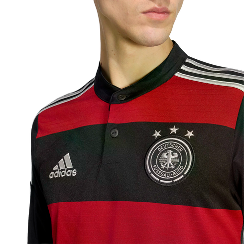 Close-up of a person wearing a red and black striped Germany football jersey featuring the Adidas logo and the DFB crest with three stars.