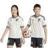 Two smiling children pose in matching white Japan soccer jerseys with colorful stripes and black shorts. The boy holds a soccer ball.