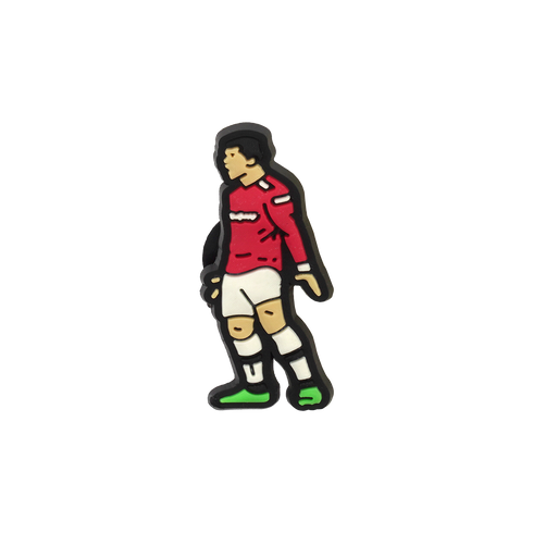A Soccer Croc Charm depicting a stylized cartoon soccer player wearing a red long-sleeved jersey, white shorts, and green-soled shoes.