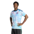 A man models a light blue and pink floral-patterned Adidas jersey with a 'CR' crest, standing with his hands on his hips against a solid black background.
