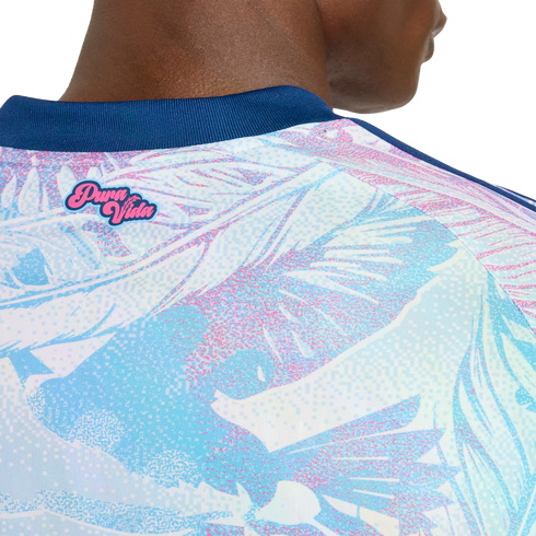 Close-up of a person's upper back wearing a light blue and pink tropical print jersey with a navy blue collar and a pink "Pura Vida" logo.