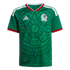 Green Mexico soccer jersey featuring an intricate Aztec graphic, white shoulder stripes, and red trim on the collar and cuffs. The team crest and Adidas logo are on the chest.