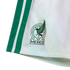 Close-up of white athletic shorts featuring two vertical green side stripes and the official Mexico national football team crest.