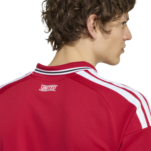 Close-up from behind of a man wearing a red jersey with three white stripes on the shoulder and "UNITED" printed on the back neck.