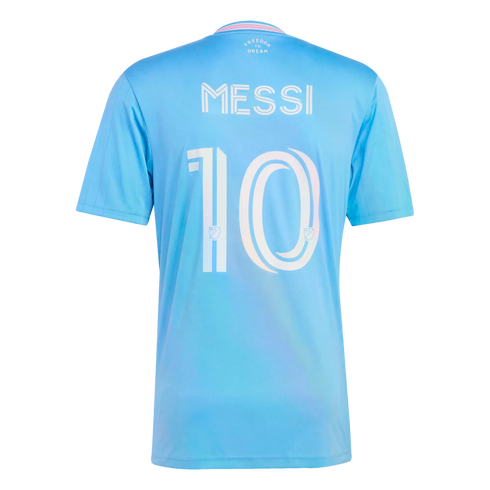 Back view of a light blue soccer jersey with "MESSI" and the number "10" in white stylized font. The collar has pink trim and "FREEDOM TO DREAM" printed below it.