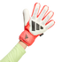 A hand wearing a red and white Adidas Predator goalkeeper glove with black details and a light green long-sleeved shirt against a black background.