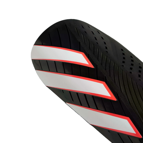 Close-up of a black athletic shin guard featuring three diagonal white stripes with red outlines.