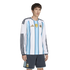 A man wearing an Argentina long-sleeve soccer jersey with light blue stripes and gold accents, and matching dark grey shorts.