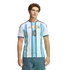 A man with curly hair wearing an Argentina soccer jersey with the number 10 and blue jeans, posed against a black background.